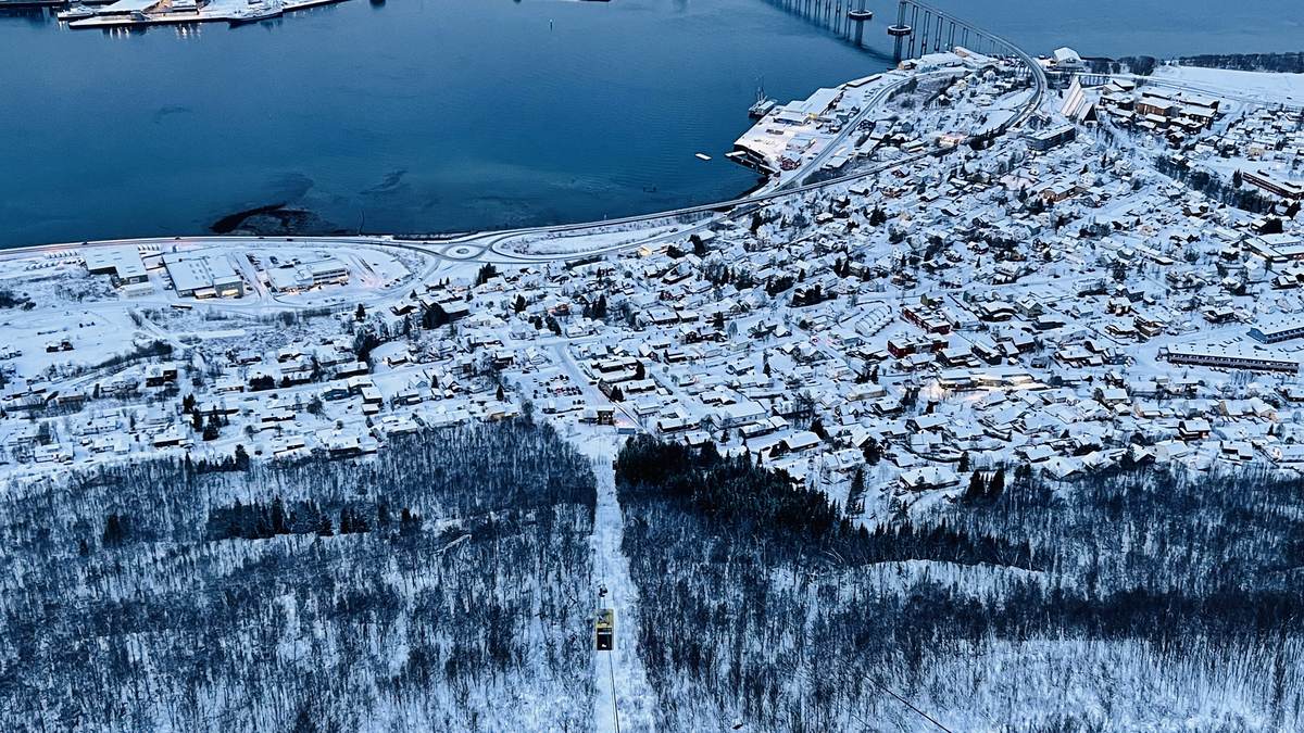 Tromsø city and harbour covered in snow during blue hour, with the cable car descending in the foreground