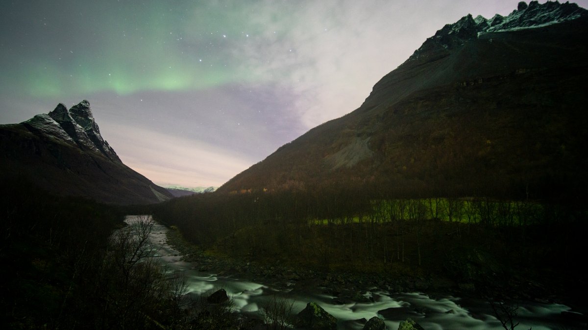 Faint aurora over a river valley with bare mountains near Tromsø in October