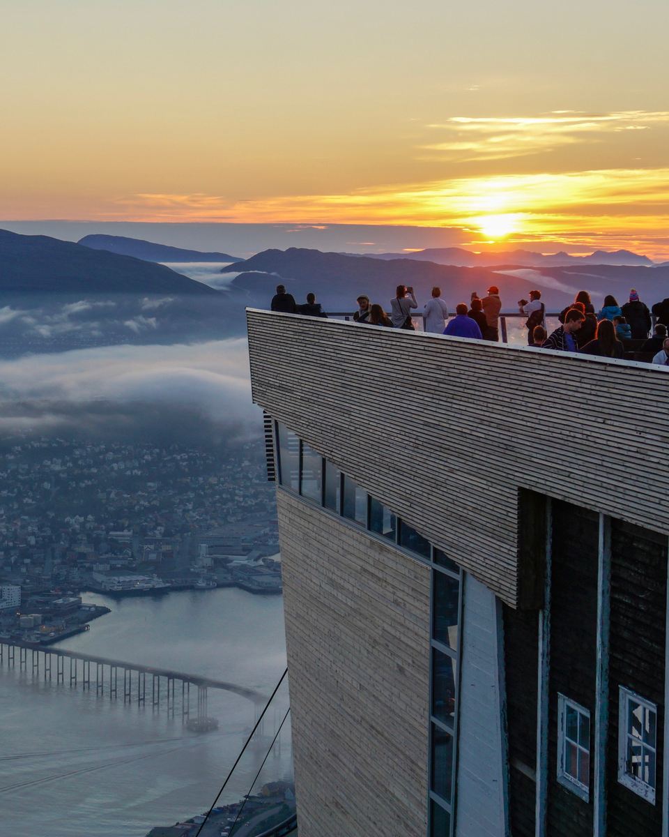 Visitors watching the midnight sun from Fjellheisen viewing platform above Tromsø