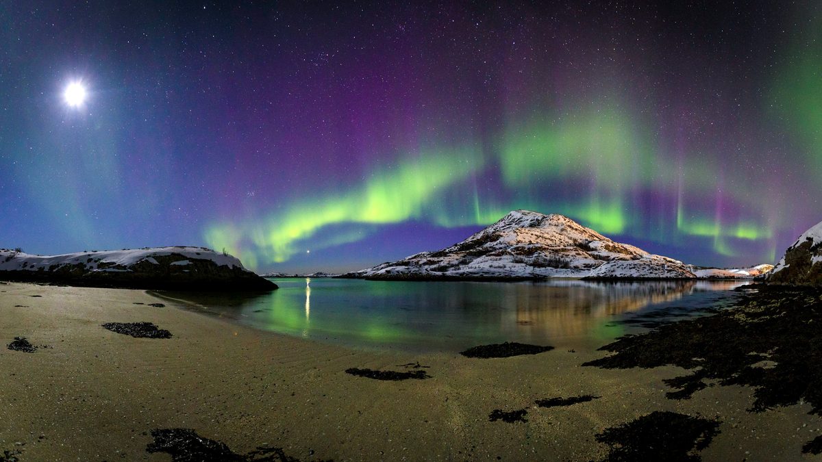 Vertical aurora beam over a coastal beach near Tromsø in late March