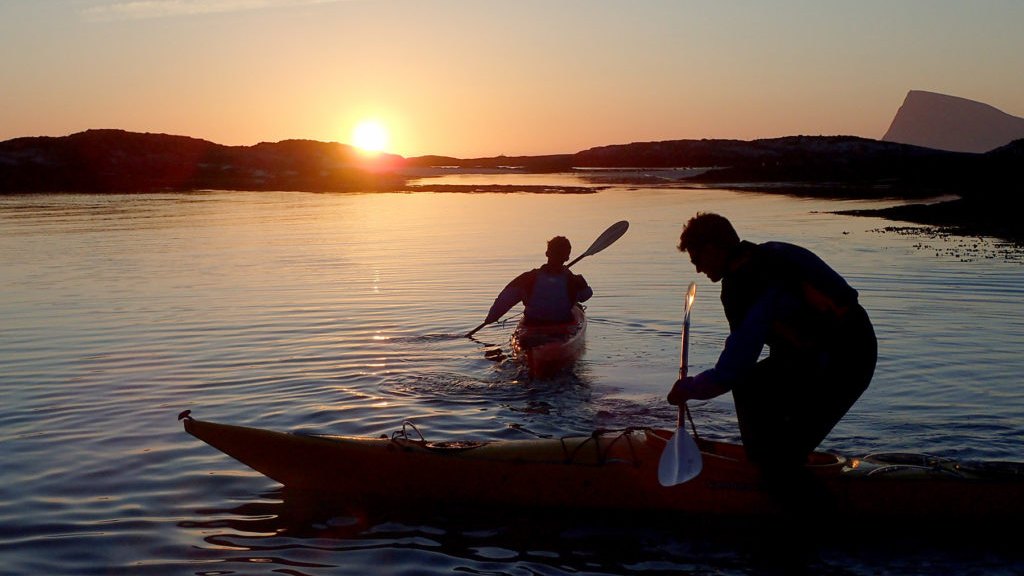 Two people sea kayaking on calm water near Tromsø under the midnight sun
