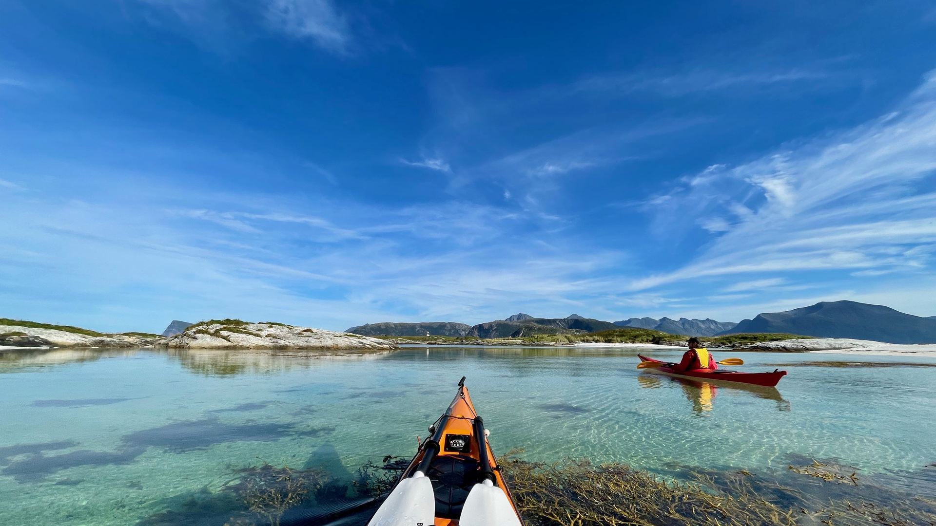 Sea kayak on clear shallow water near Sommarøy, mountains behind