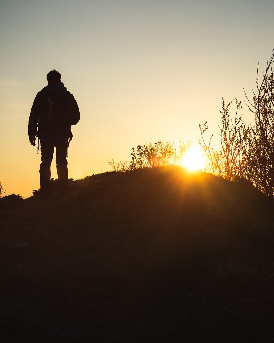 Hiker silhouetted on a ridge above Tromsø under the midnight sun
