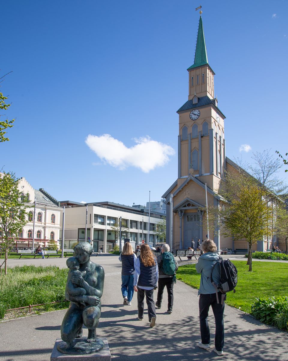 People walking through Tromsø city center past the cathedral in summer